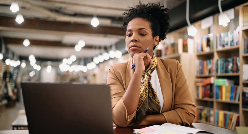 Photo of a woman looking thoughtfully at a laptop screen