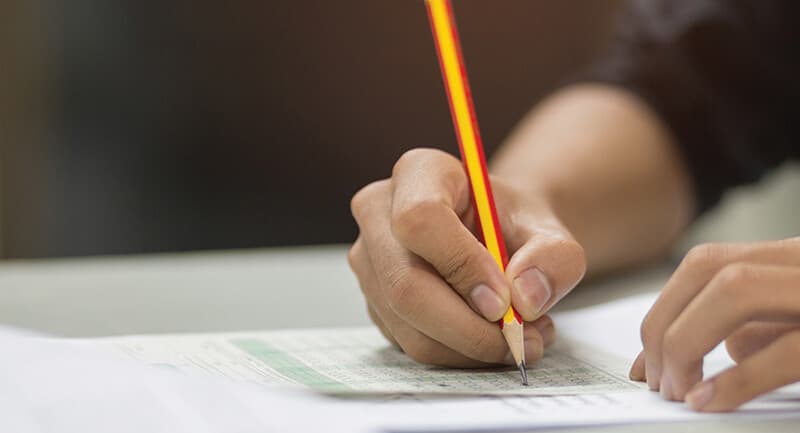 Close-up photo of a hand holding a pencil over a piece of white paper