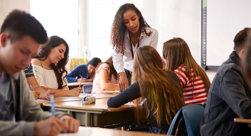 Photo of a teacher helping students in a classroom